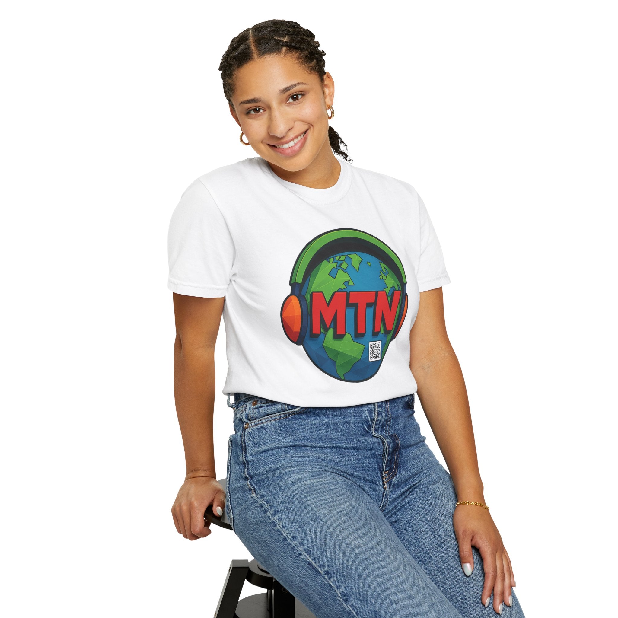 Model wearing a white MUTE the NOISE t-shirt with a colorful logo and text, sitting on a stool against a white background.